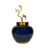 جار چینی لاکچری با درب برنزی و تزئین پرنده و شکوفه زرد روی پس‌زمینه سفید